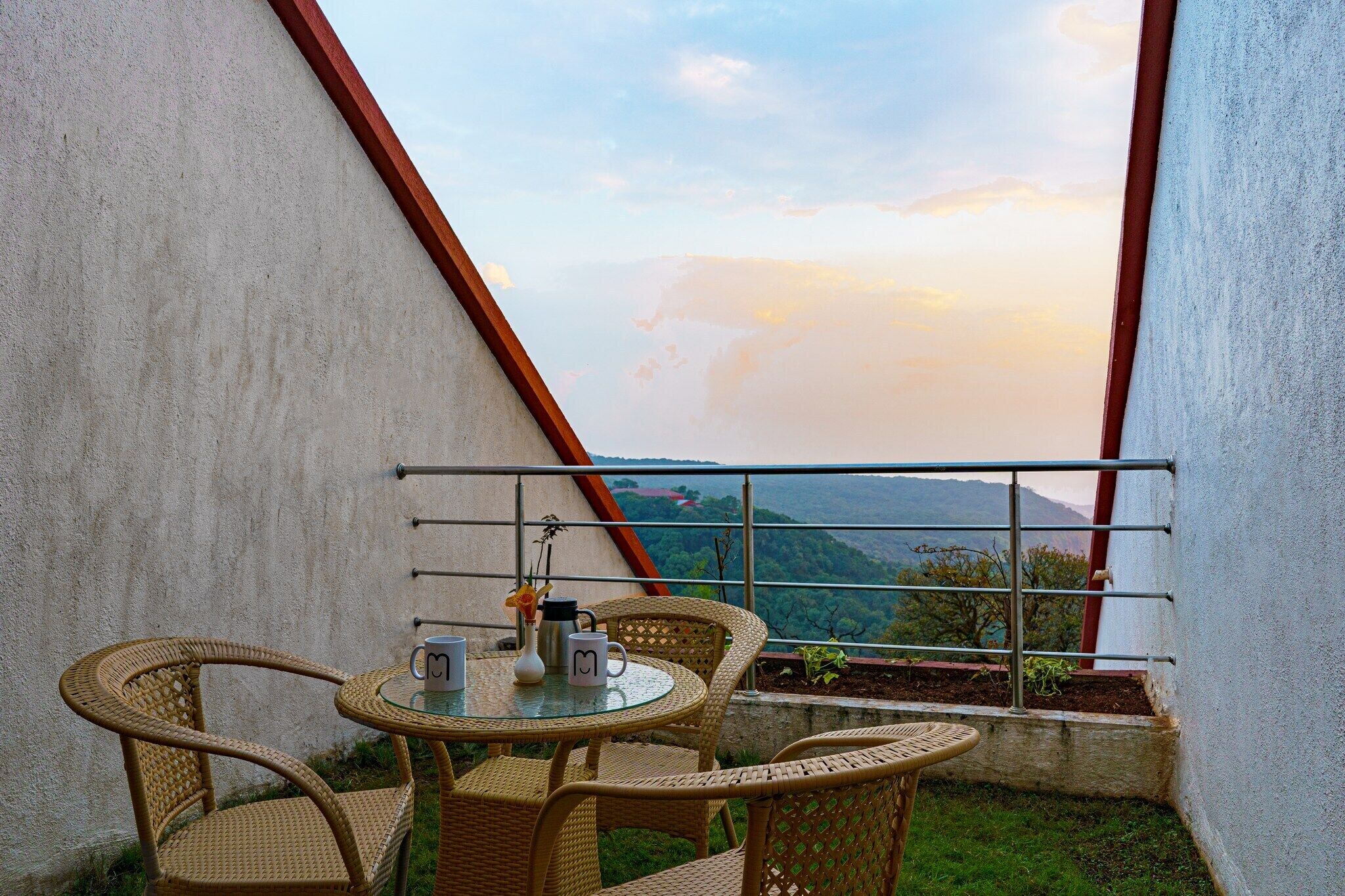 Un balcon agrémenté de fauteuils et d’une table en osier, offrant une vue sur un paysage montagneux.