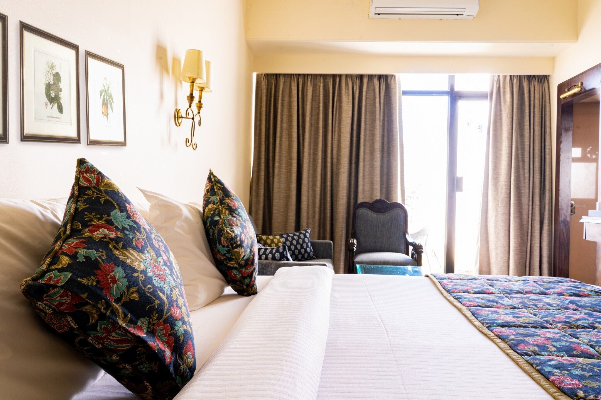 A hotel room with a large bed, two pillows, a chair, a desk, and a window with curtains.