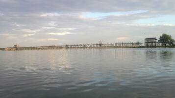 Un muelle de madera que se adentra en aguas tranquilas, con un edificio tradicional al final.