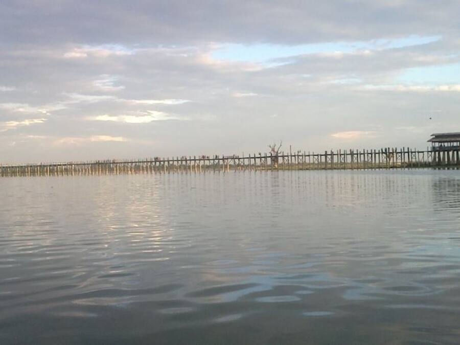 Un muelle de madera que se adentra en aguas tranquilas, con un edificio tradicional al final.