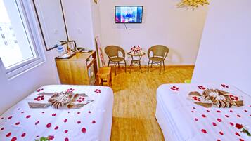 Une chambre d’hôtel avec deux lits, une télévision, un bureau et une chaise.
