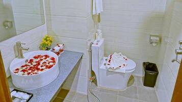 A bathroom with a white sink, a mirror, a shower, and a toilet.
