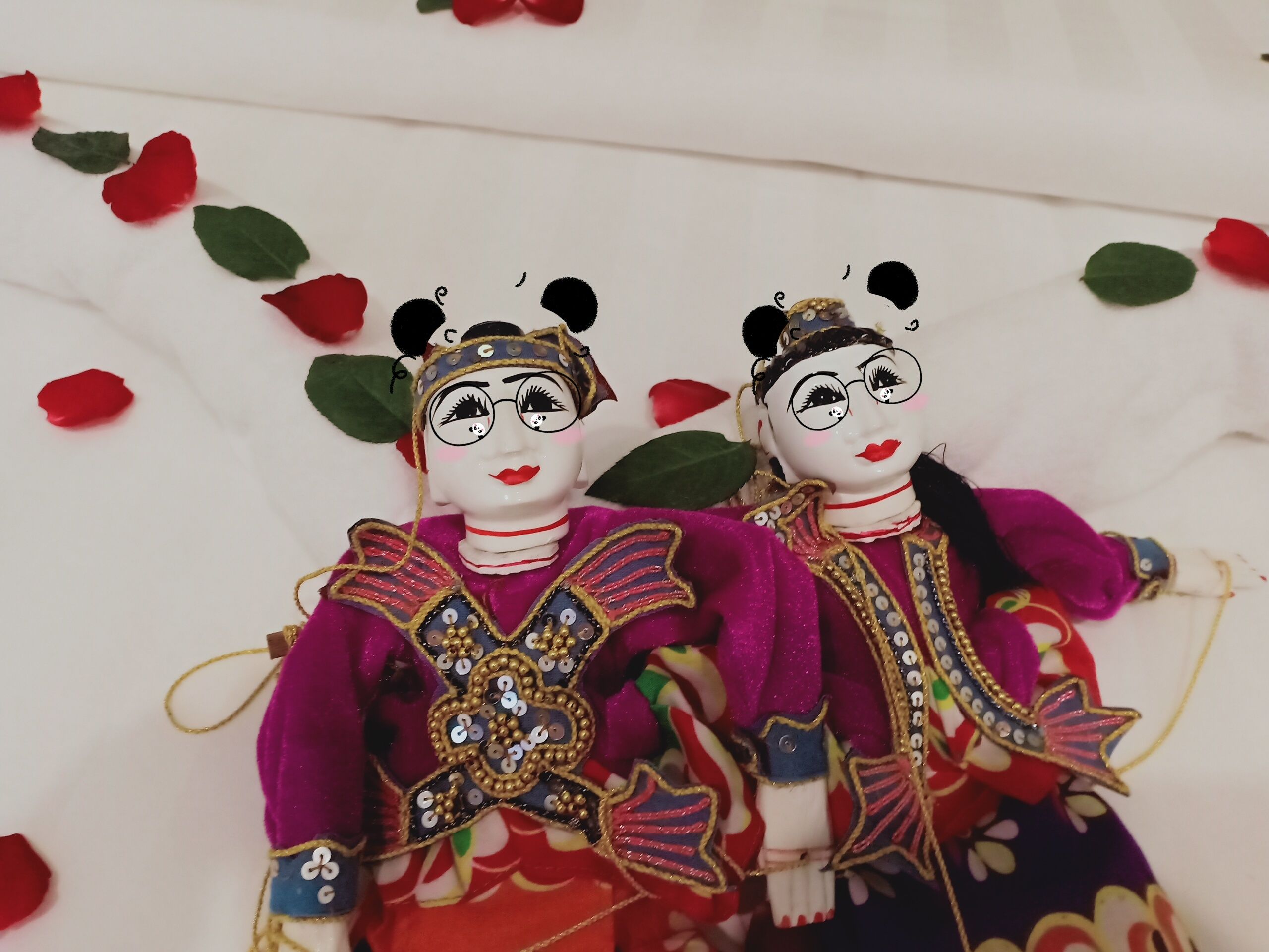 Two dolls dressed in traditional costumes with intricate designs and accessories.