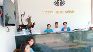 A reception desk at Hotel Duo Swan with a decorative statue, a reception desk sign, and a logo above. - Hotel Duo Swan (Mandalay)
