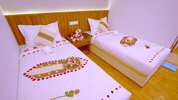 Two single beds with wooden headboards, white bedding, and decorative elements like rose petals and a mirror.