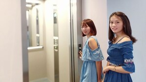 Two individuals standing in an elevator with a visible control panel and a door number sign. - Hotel Duo Swan (Mandalay)