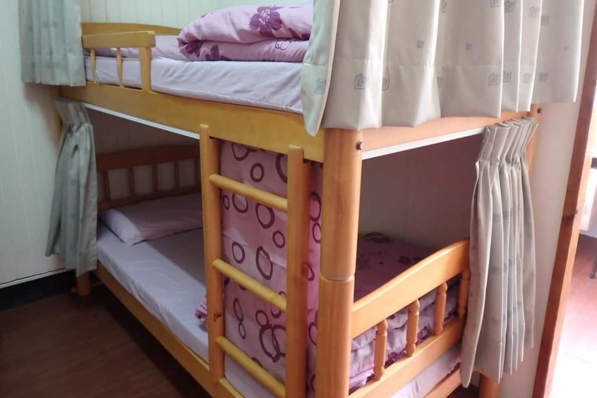 Ein Stockbett mit einer Leiter, einer unteren Schlafgelegenheit und einer oberen mit einem Kopfkissen.