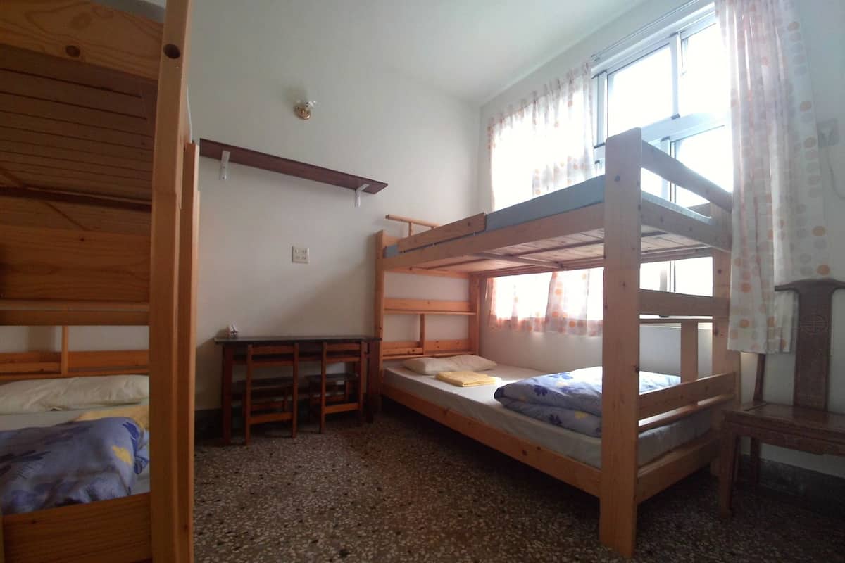 Ein Schlafraum mit Etagenbett, Schreibtisch und einem Fenster mit Vorhängen.