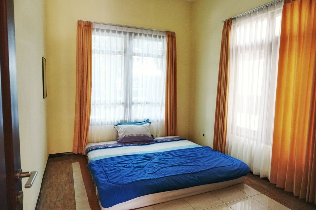 A bedroom with a bed, curtains, and a window.