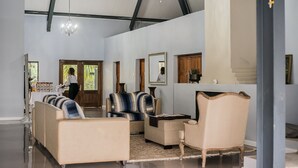 A spacious living room with a high ceiling, a chandelier, and a large mirror. There are multiple seating options including sofas and armchairs. - Mount Shekinah Country Hotel (Balgowan)