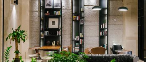 A modern living room with a sofa, chairs, a coffee table, and a bookshelf against a stone wall.