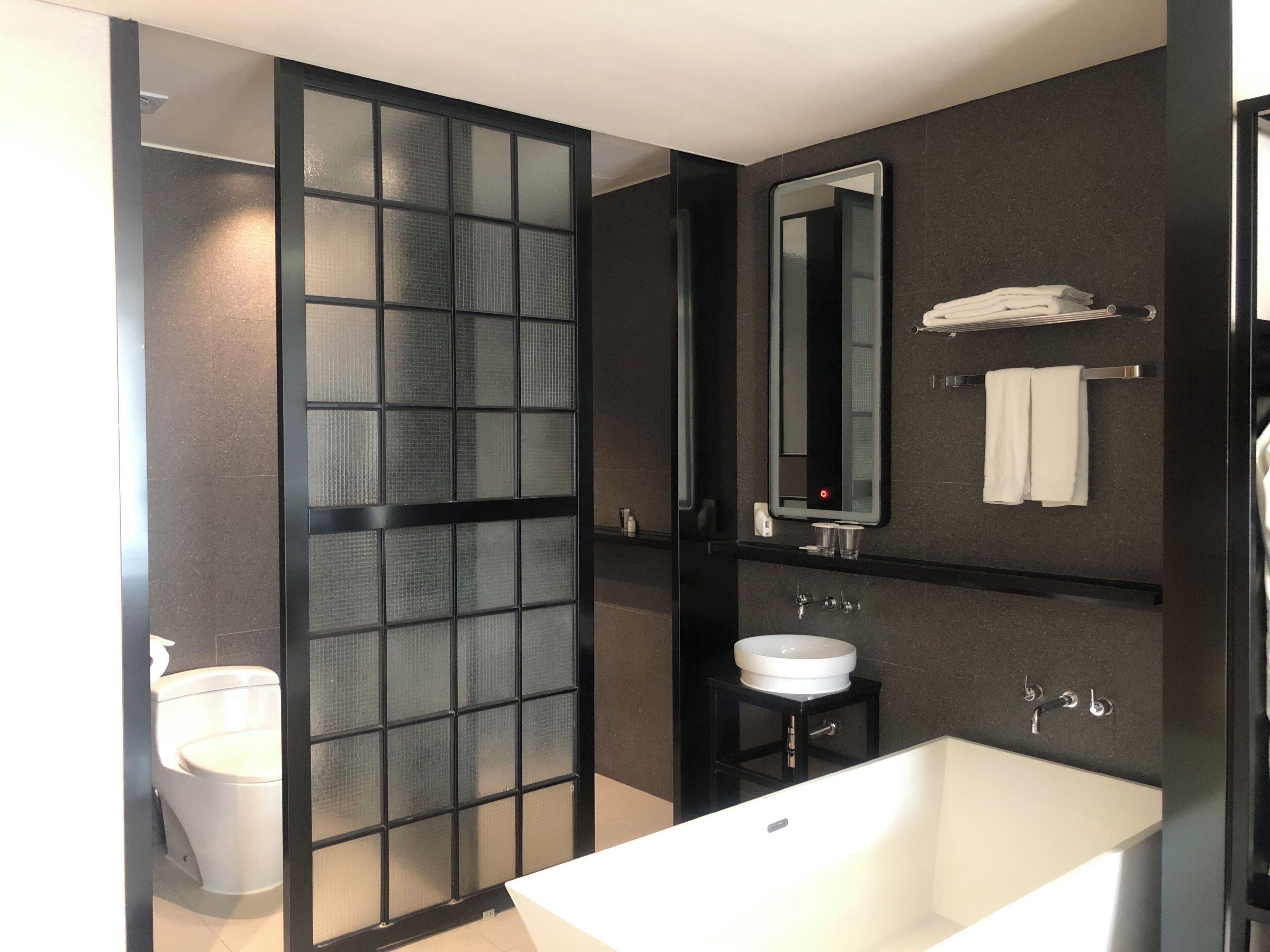 A modern bathroom with a large mirror, a white sink, and a bathtub.