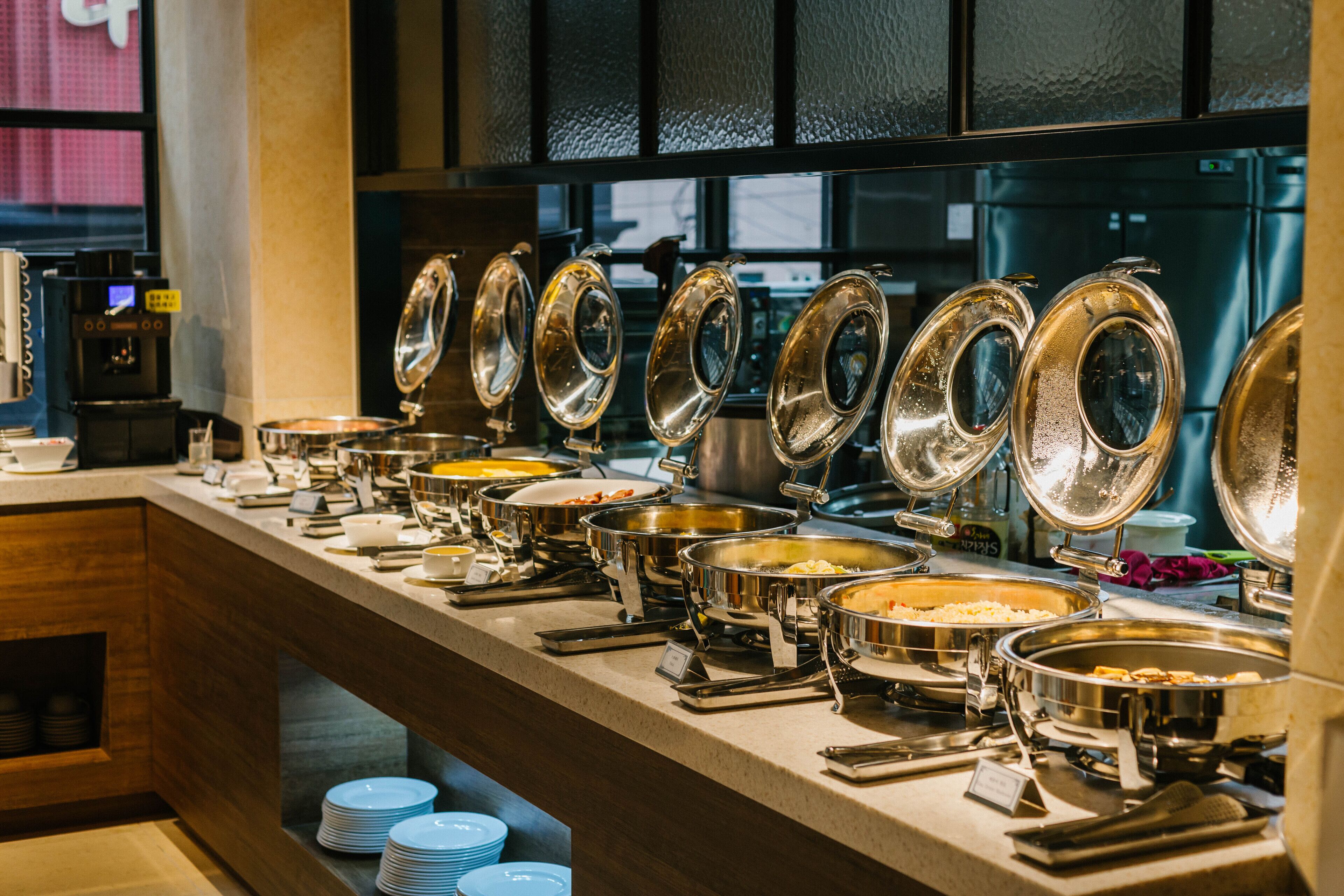 Montaje de bufé con varias estaciones de comida y una máquina de café.