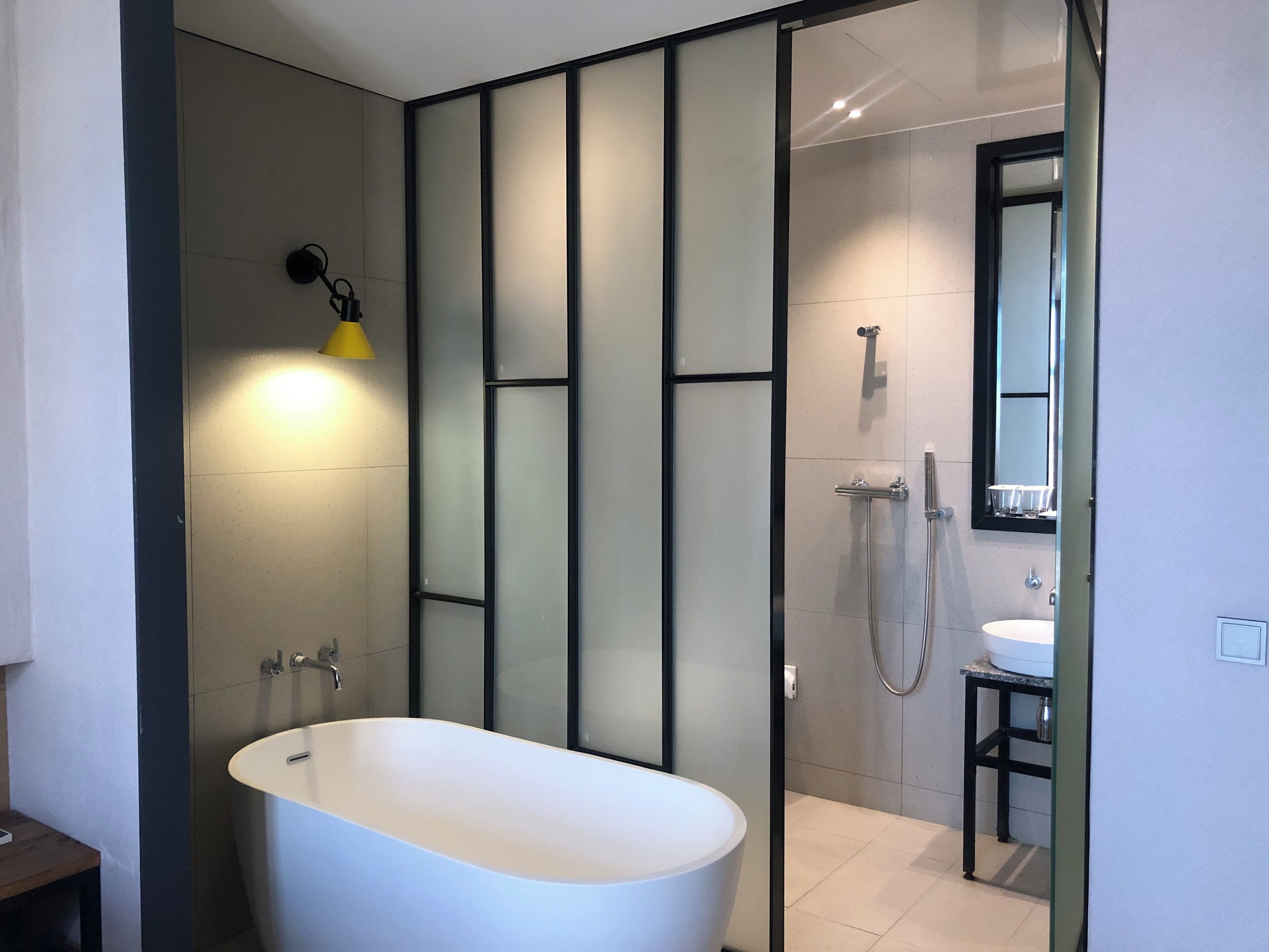 A modern bathroom with a freestanding bathtub, a glass shower enclosure, and a visible sink area.