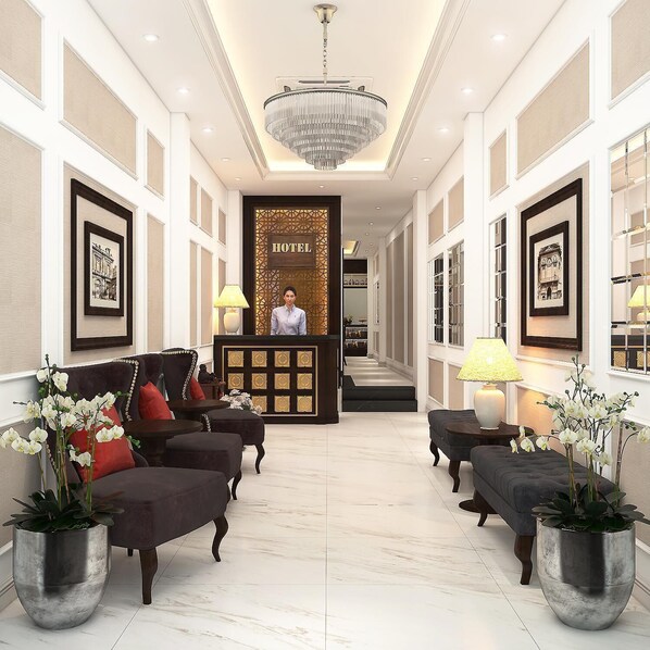 A hotel lobby with a reception desk, framed artwork on the walls, and seating areas with potted plants.