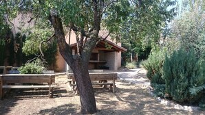 Un'area salotto esterna rustica con panche di legno e un edificio in mattoni sullo sfondo.