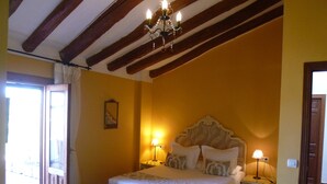 Camera da letto con un letto, lampade da comodino, un lampadario e una porta che dà su un balcone.
