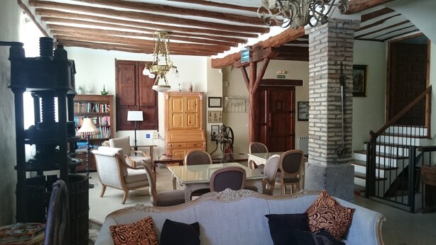 Un accogliente soggiorno con zona pranzo, travi in legno, un lampadario e un camino.