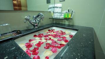 Un lavabo de salle de bain orné de pétales de rose, avec un miroir au-dessus.