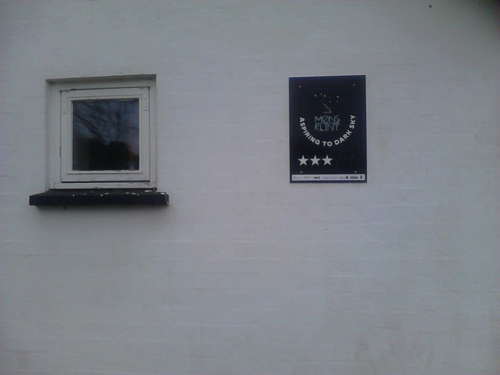 Ein weißes Gebäude mit einem Fenster und einem Schild an der Wand.