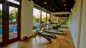 Un gimnasio con cintas de correr, una bicicleta estática y una prensa de banca.