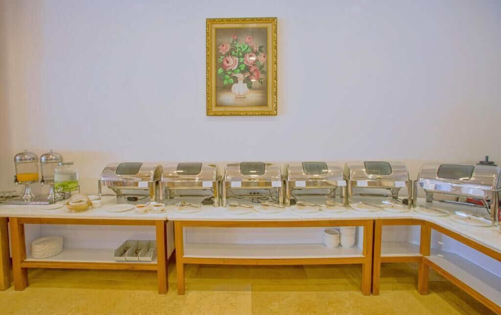 A buffet setup with multiple serving stations, a framed floral artwork on the wall, and a wooden buffet table.