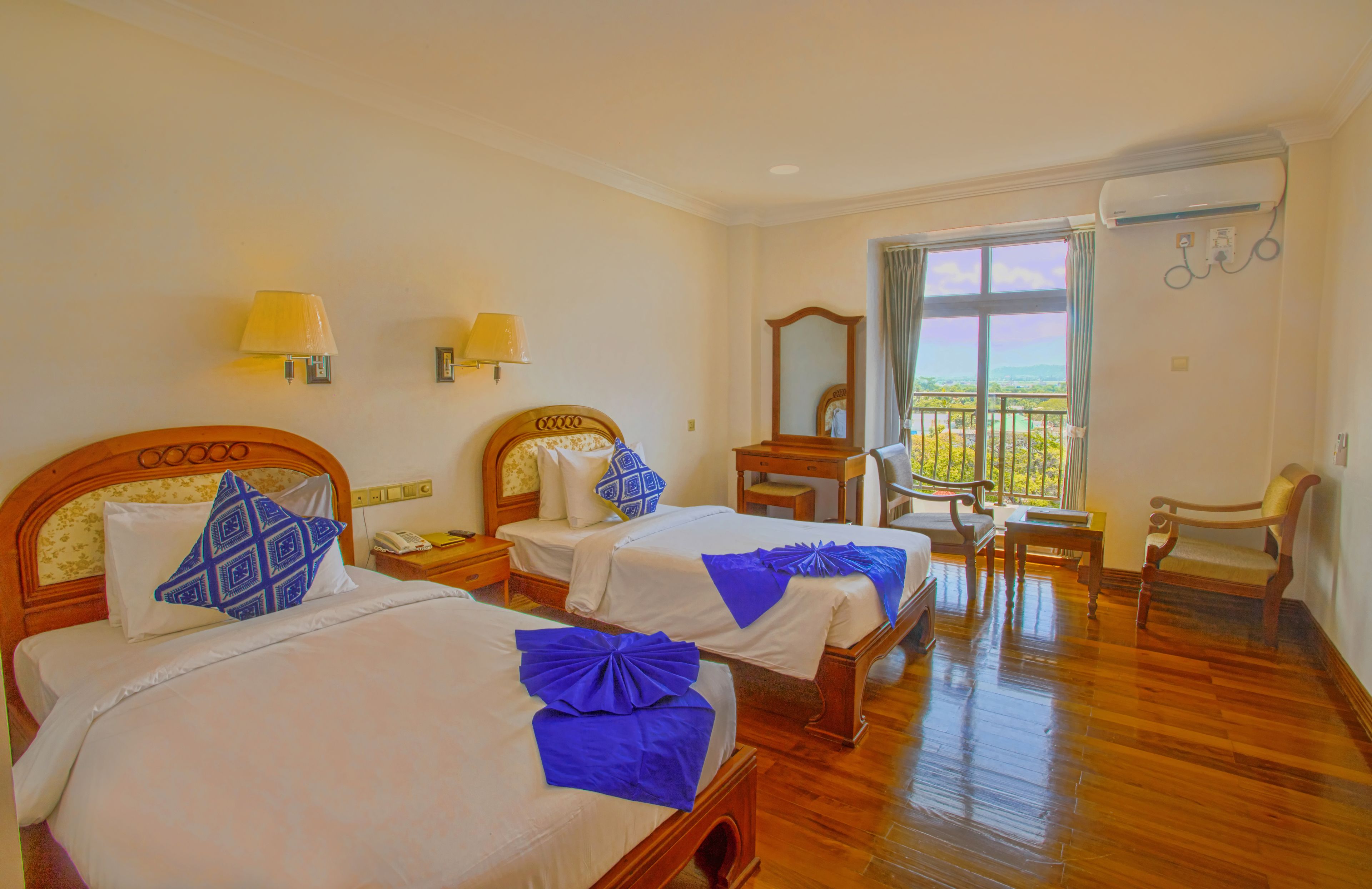 Habitación de hotel con dos camas, un balcón, una silla y un escritorio.