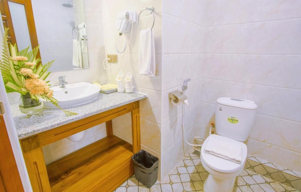 Ein Badezimmer mit Waschbecken, Spiegel, Handtuchhalter und Toilette.