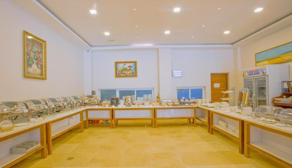 Une salle de conférence équipée de longues tables, de chaises et de tables où la nourriture est présentée en buffet.
