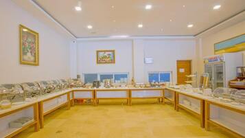 Un salón de conferencias con mesas largas, sillas y estaciones de comida tipo buffet.
