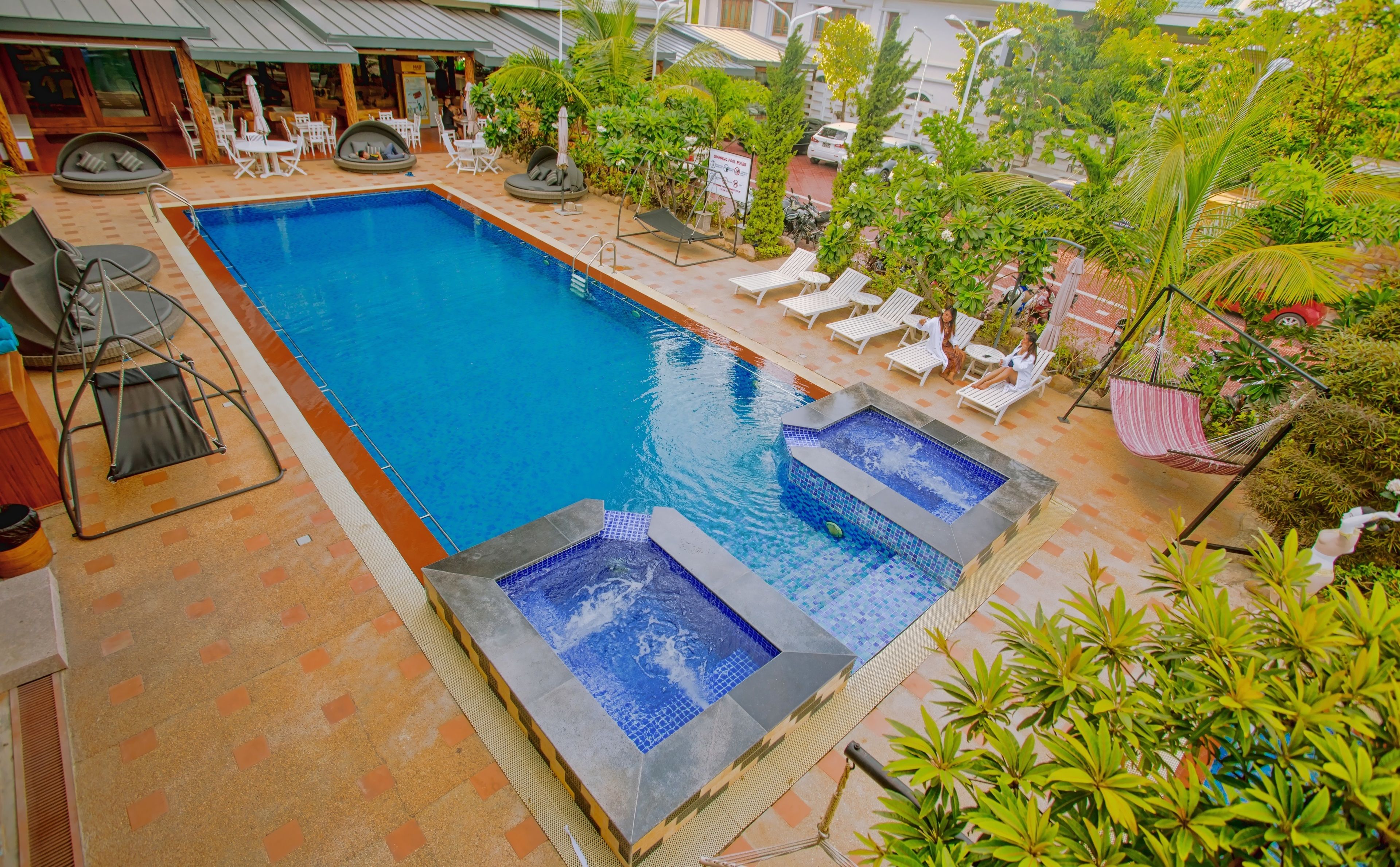 A swimming pool with lounge chairs and a hot tub area.