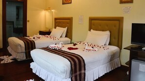 Une chambre d’hôtel avec deux lits, une télévision et des œuvres d’art accrochées aux murs.