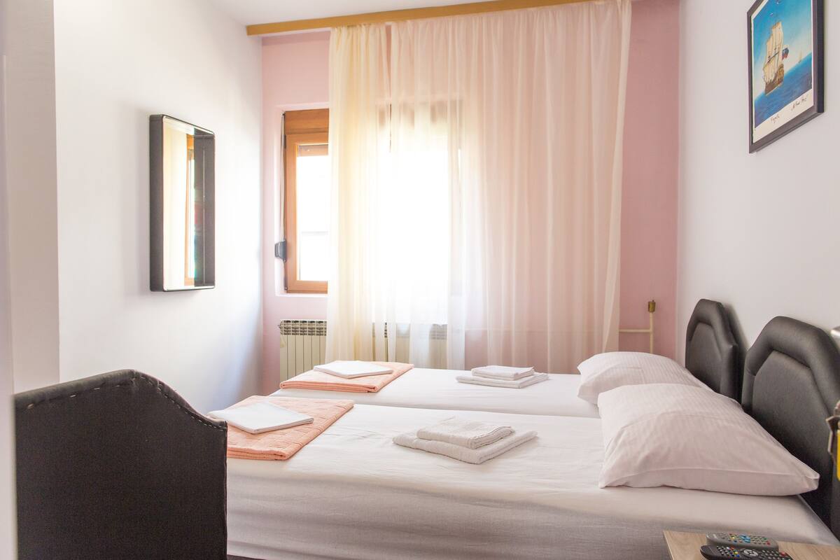 Una habitación de hotel con dos camas, una silla y un cuadro en la pared.