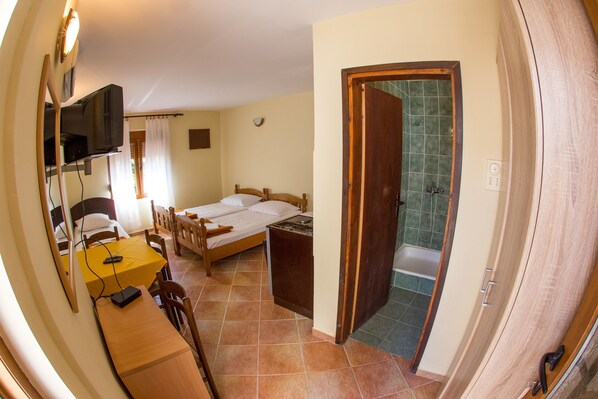 A room with a bed, a desk, a chair, a television, and a bathroom with a shower. - Guest House Blue Coast (Budva)