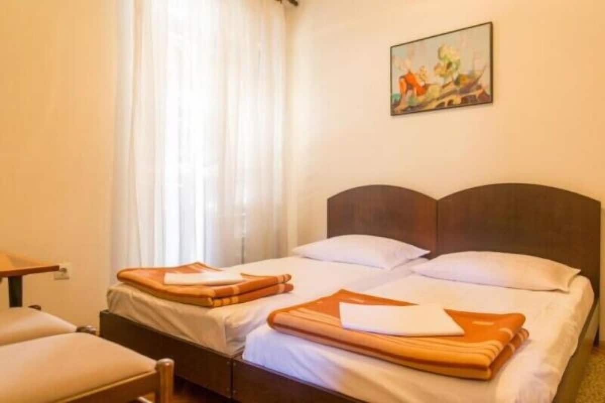 Una habitación de hotel con una cama, una silla y un cuadro en la pared.