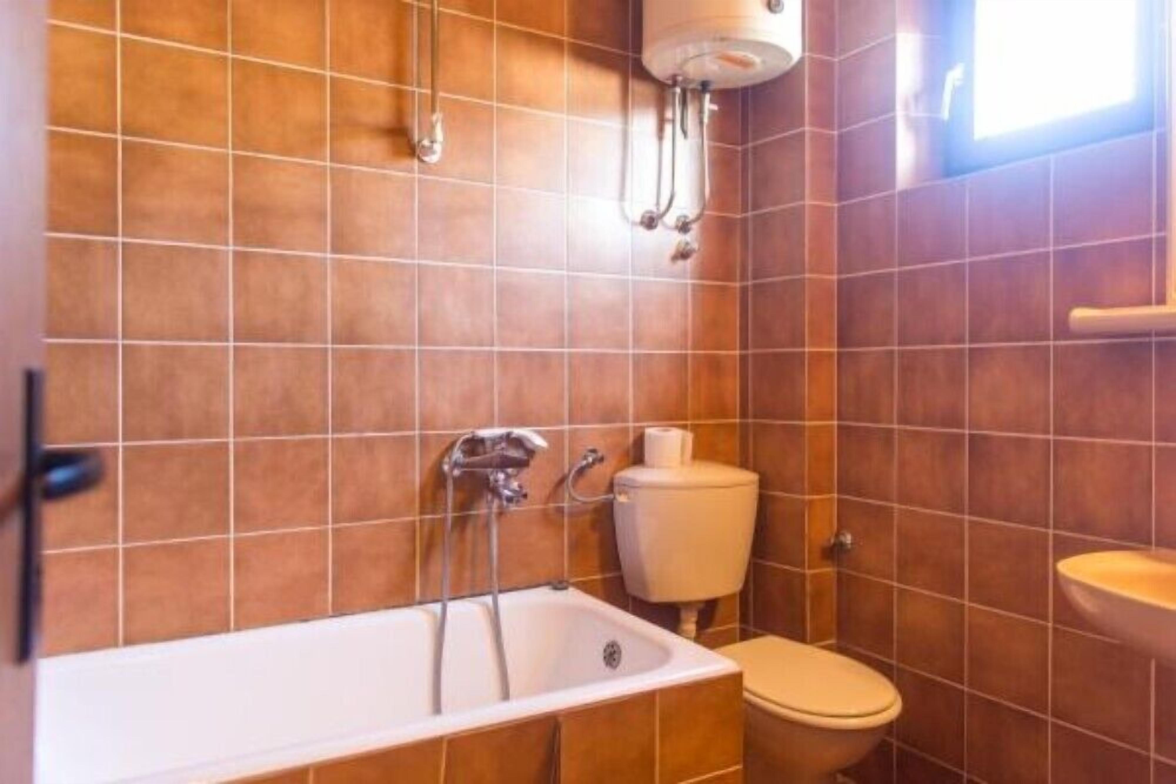 A bathroom with a bathtub, toilet, and sink, all tiled in a uniform color.