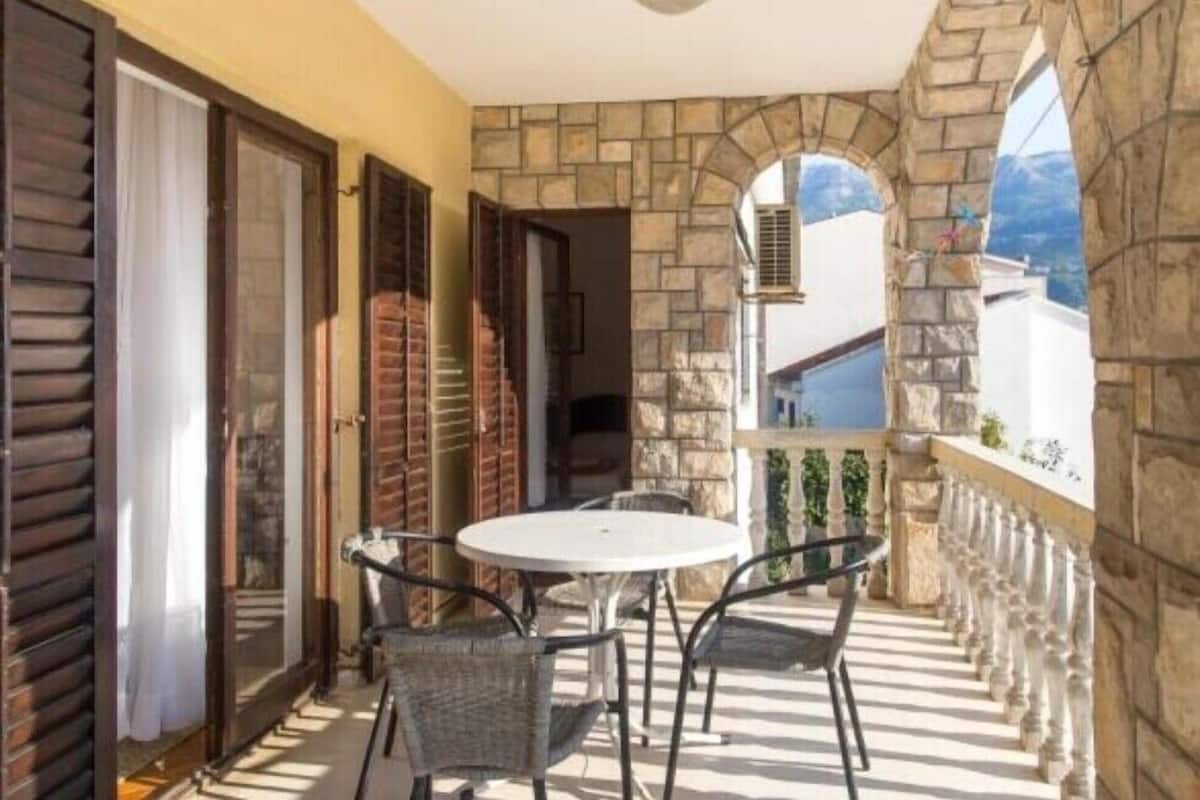 Un balcón con pared de piedra, una mesa redonda y dos sillas.