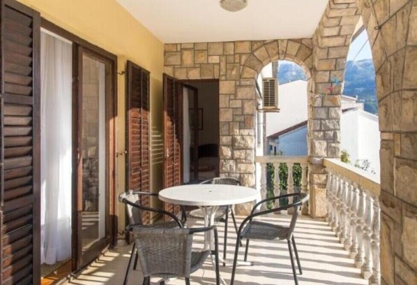 Un balcon avec un mur en pierre, une table ronde et deux chaises.