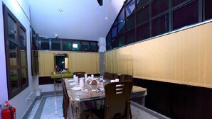 A dining area with a marble floor, a glass-top table, and wooden chairs. - Hotel-All Season Lodge (Sylhet)
