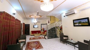 A spacious living area with a staircase, a chandelier, and a television. - Hotel-All Season Lodge (Sylhet)