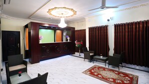 A hotel lobby with a reception desk, seating area, and a chandelier. - Hotel-All Season Lodge (Sylhet)