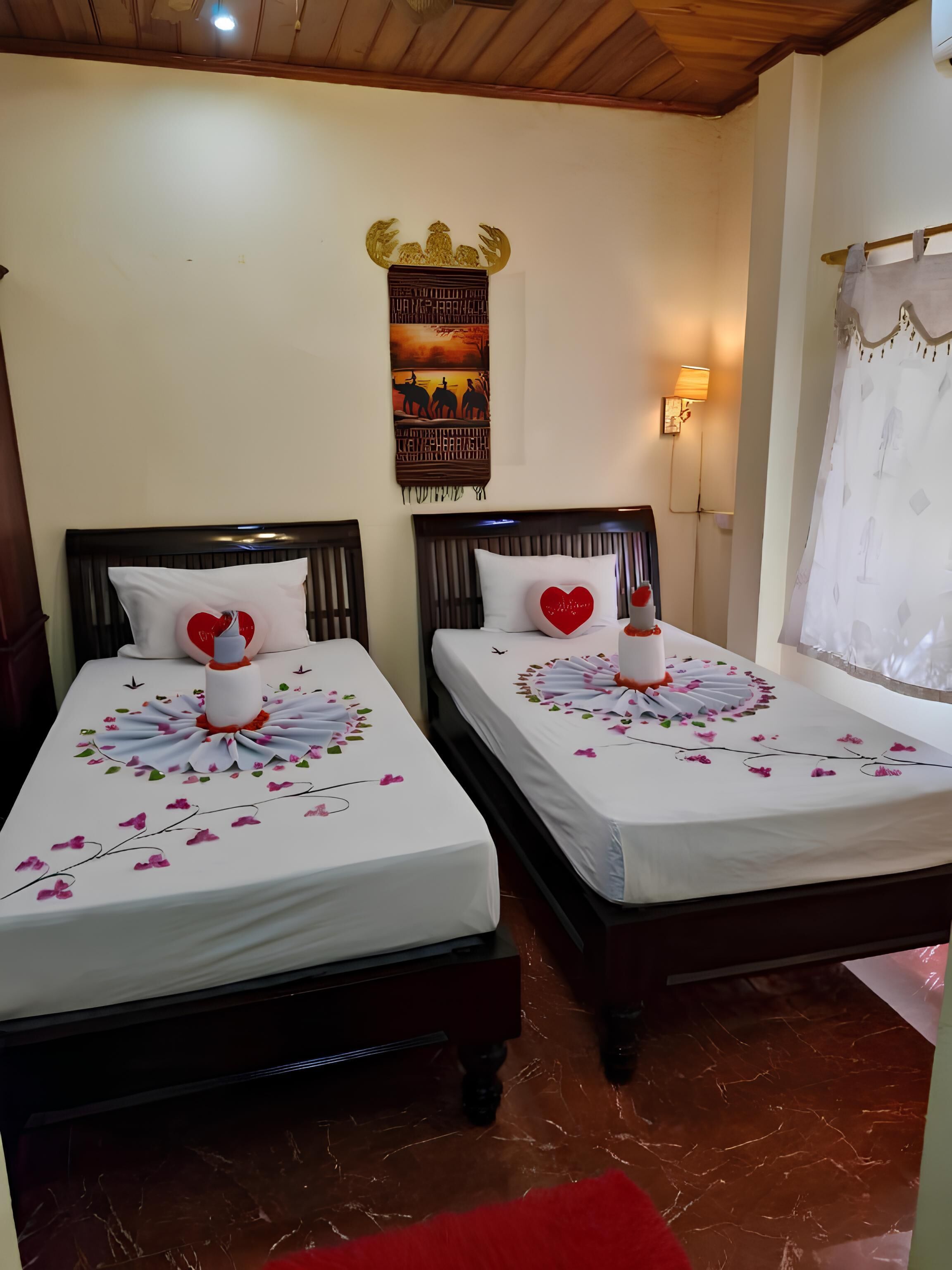 Two beds with floral arrangements, a wall hanging, and a lamp.
