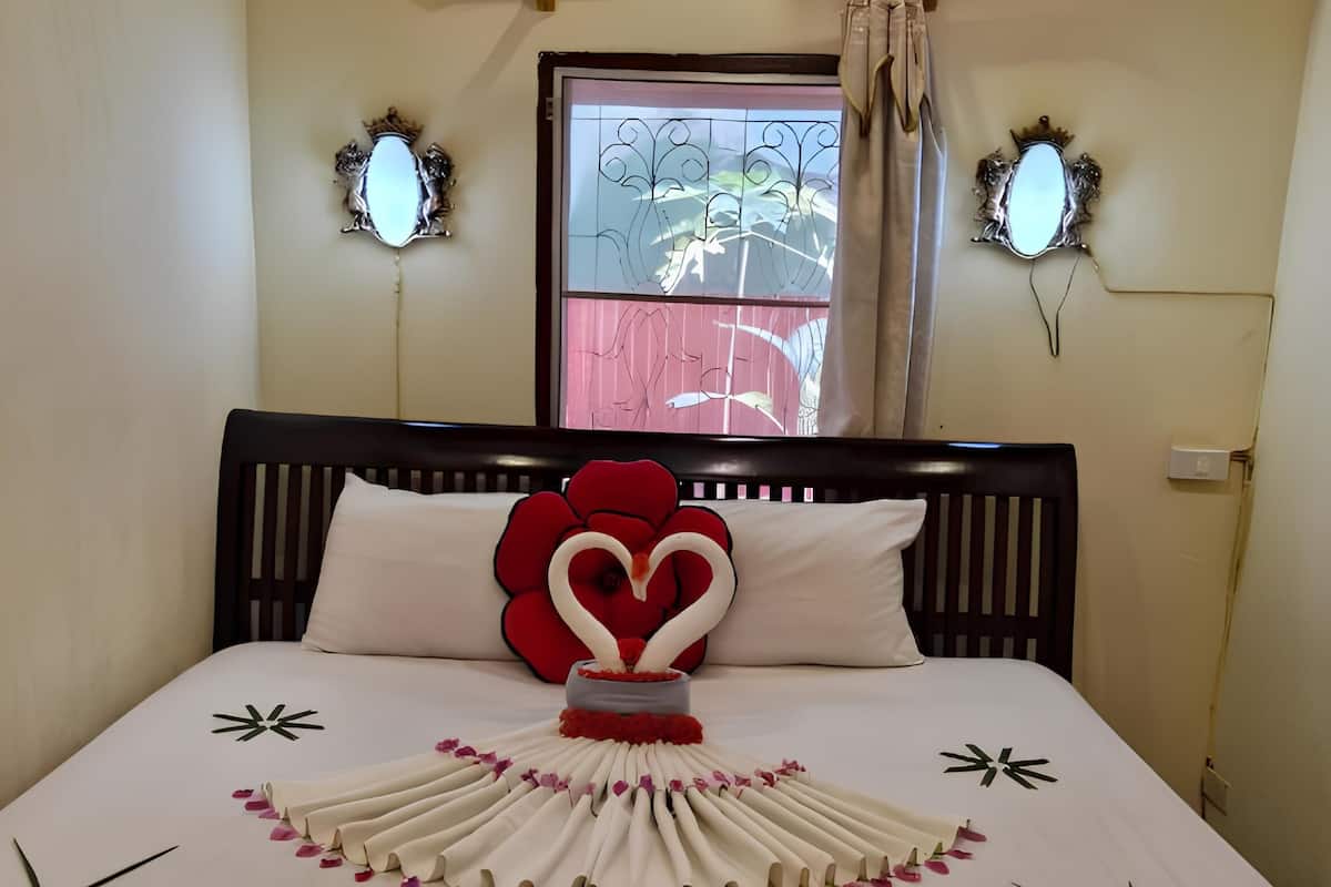 Una cama cuidadosamente arreglada con un adorno con forma de corazón y la palabra 'LOVE' escrita con flores.