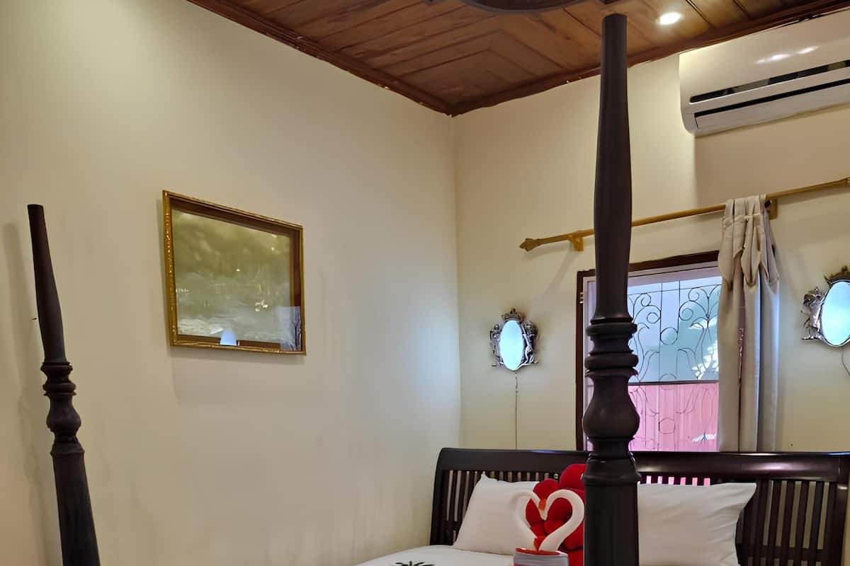 Un dormitorio con cama con dosel, un cuadro enmarcado en la pared y una ventana con cortinas.