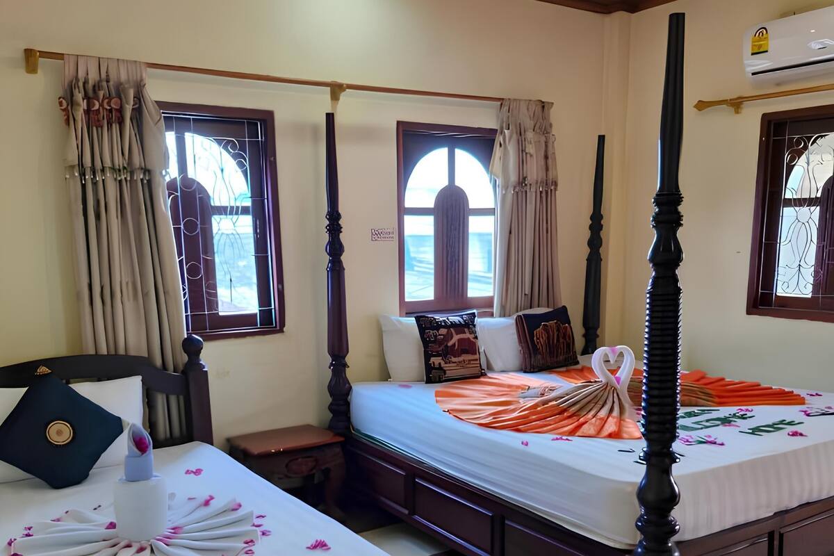 Habitación de hotel con dos camas con dosel, piso de cuadros y ventana con cortinas.