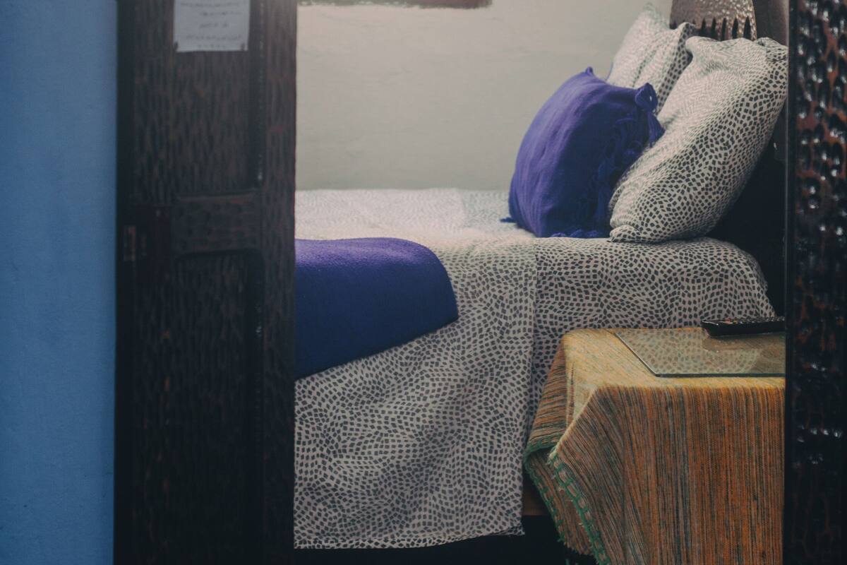 A room with a bed, a small table, and a window with a view.