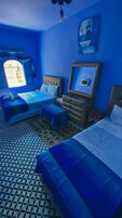 Una habitación con cama, escritorio, silla y ventana con cortinas.