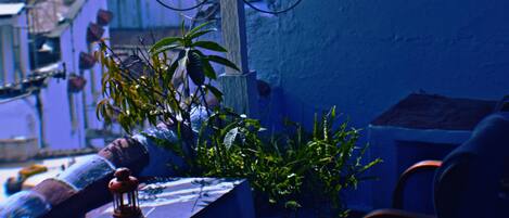 A balcony with a table, chairs, hanging plants, and a satellite dish.
