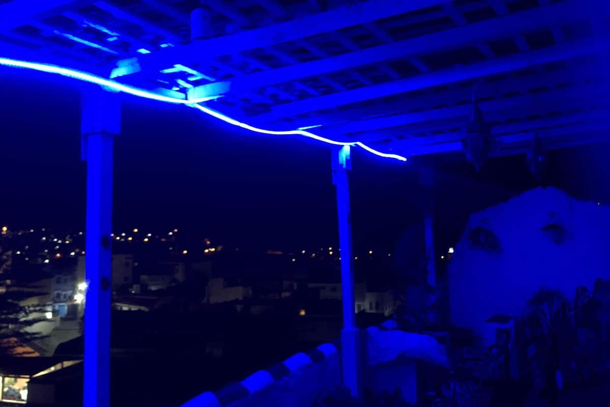 A covered outdoor seating area with a view of a cityscape at night.