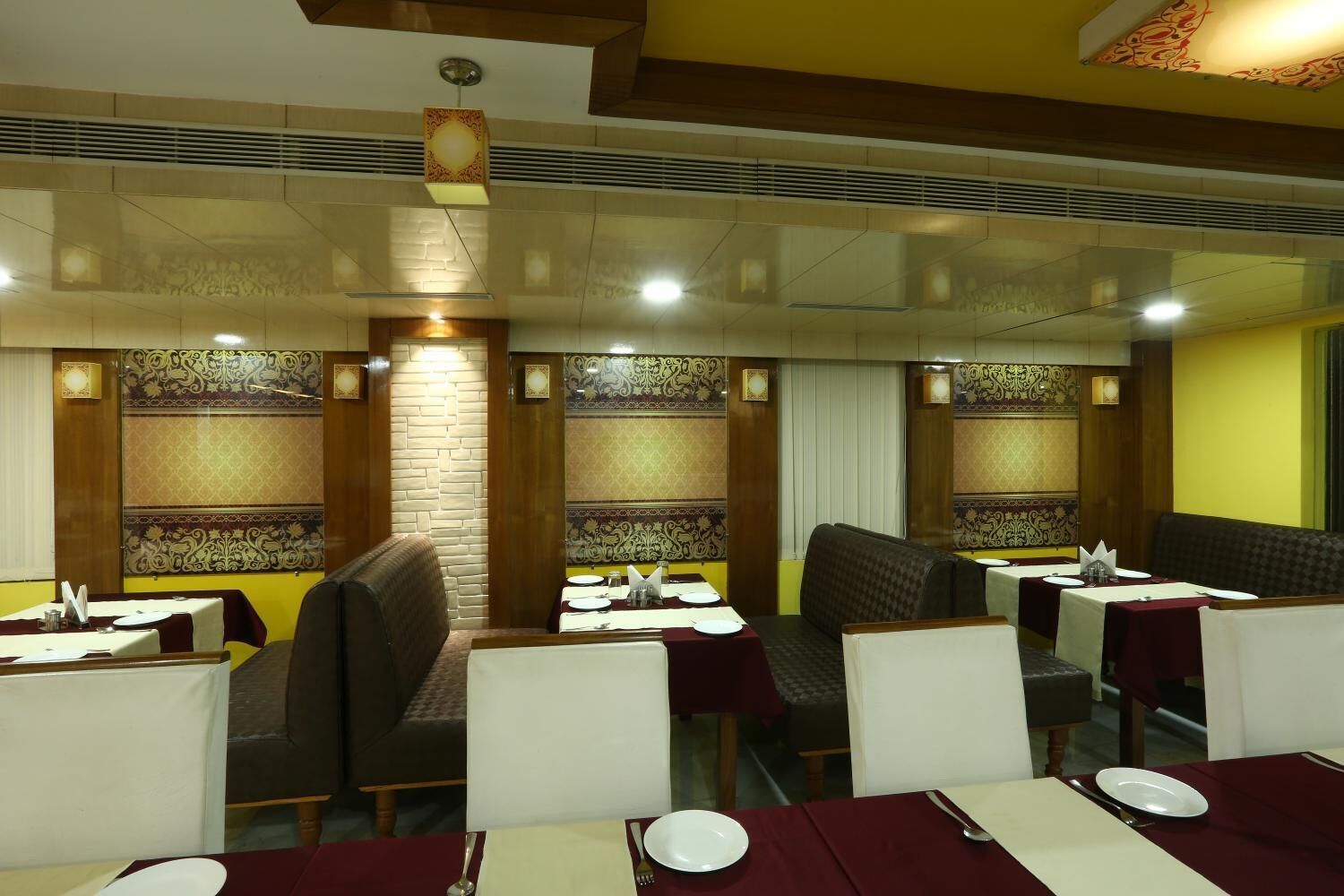 A restaurant with booths and tables, each with a white tablecloth and silverware.